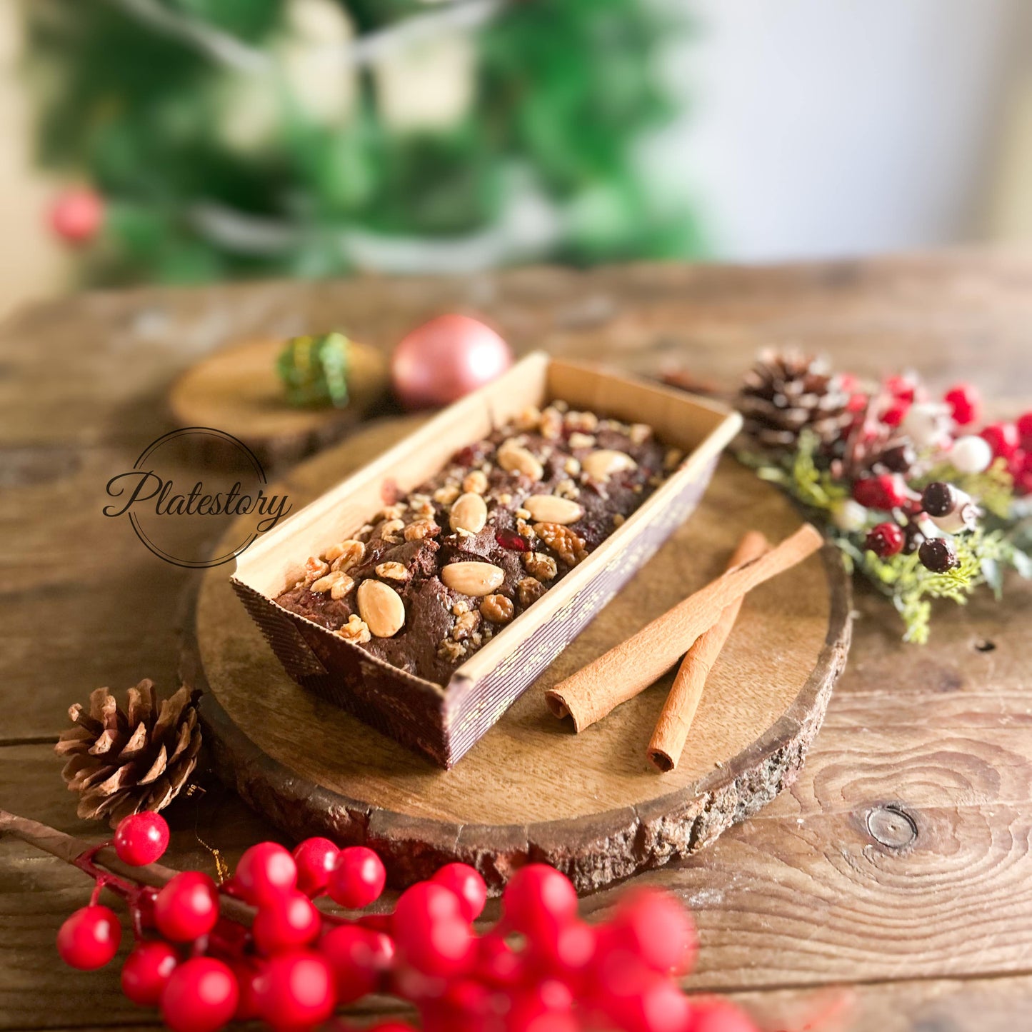 Chocolate dessert with nuts on a wooden board in front of a Christmas tree.