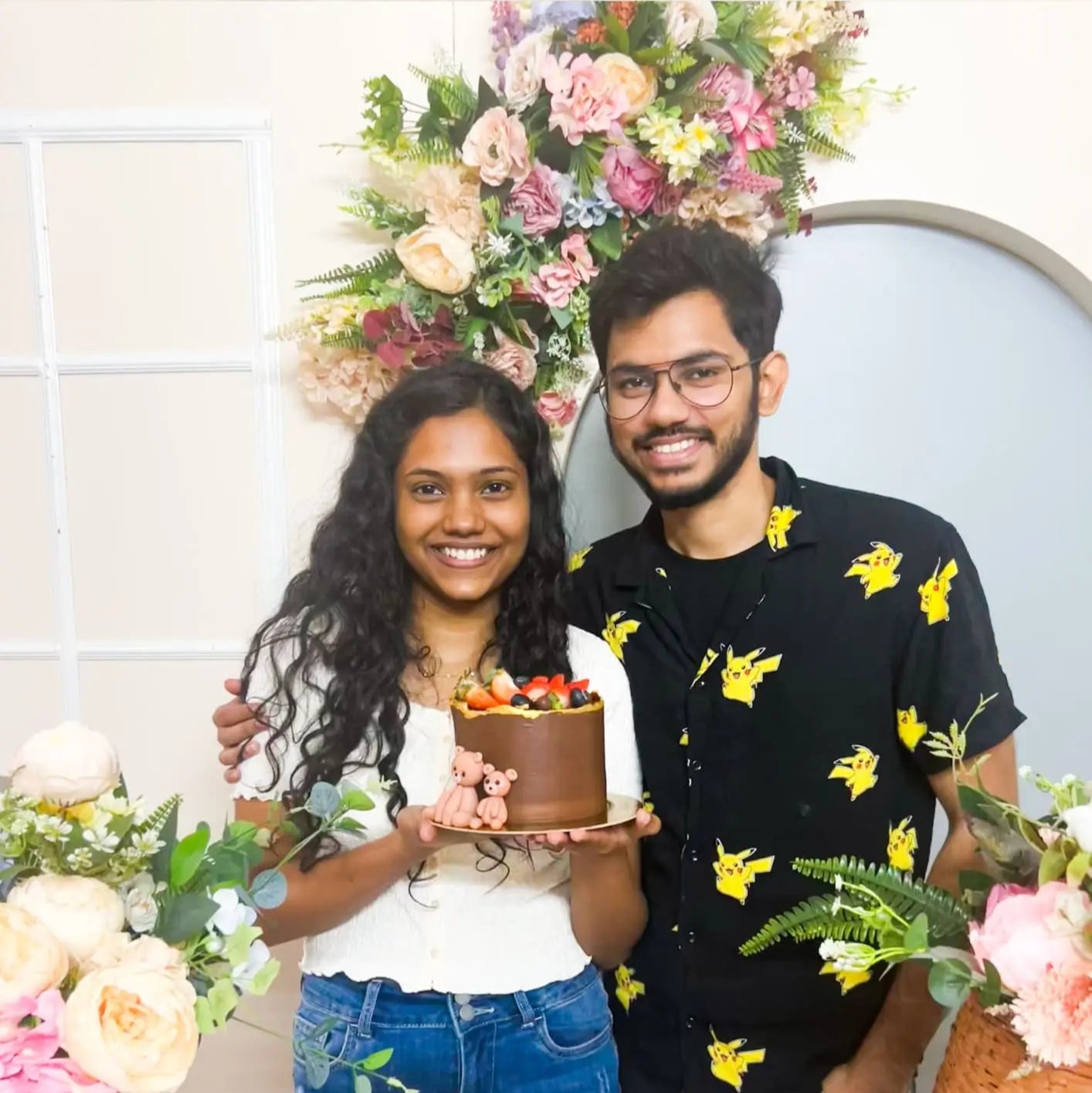 A promotional image featuring two adults, a man, and a woman, smiling and holding a baked dessert, with decorative elements in the background such as flowers and a sign reading 'Baking Date at Plate Story Anna Nagar'.