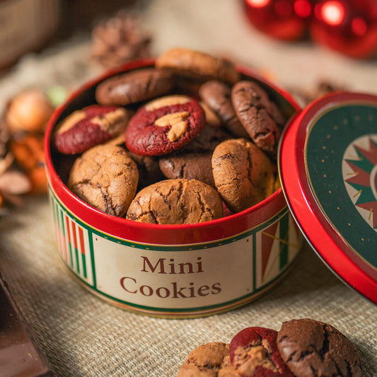 Mini cookies in a decorative tin with Christmas ornaments in the background