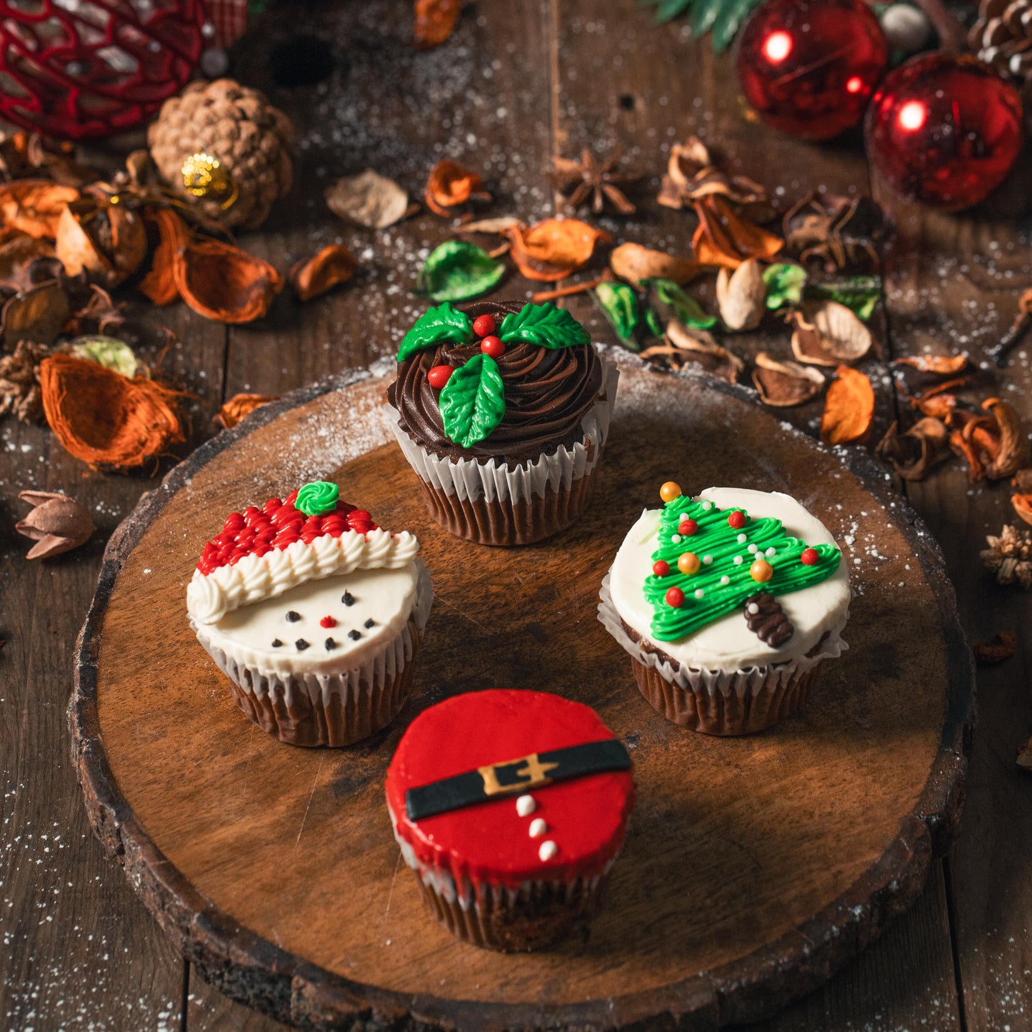 Decorative cupcakes on a wooden board with Christmas decorations in the background