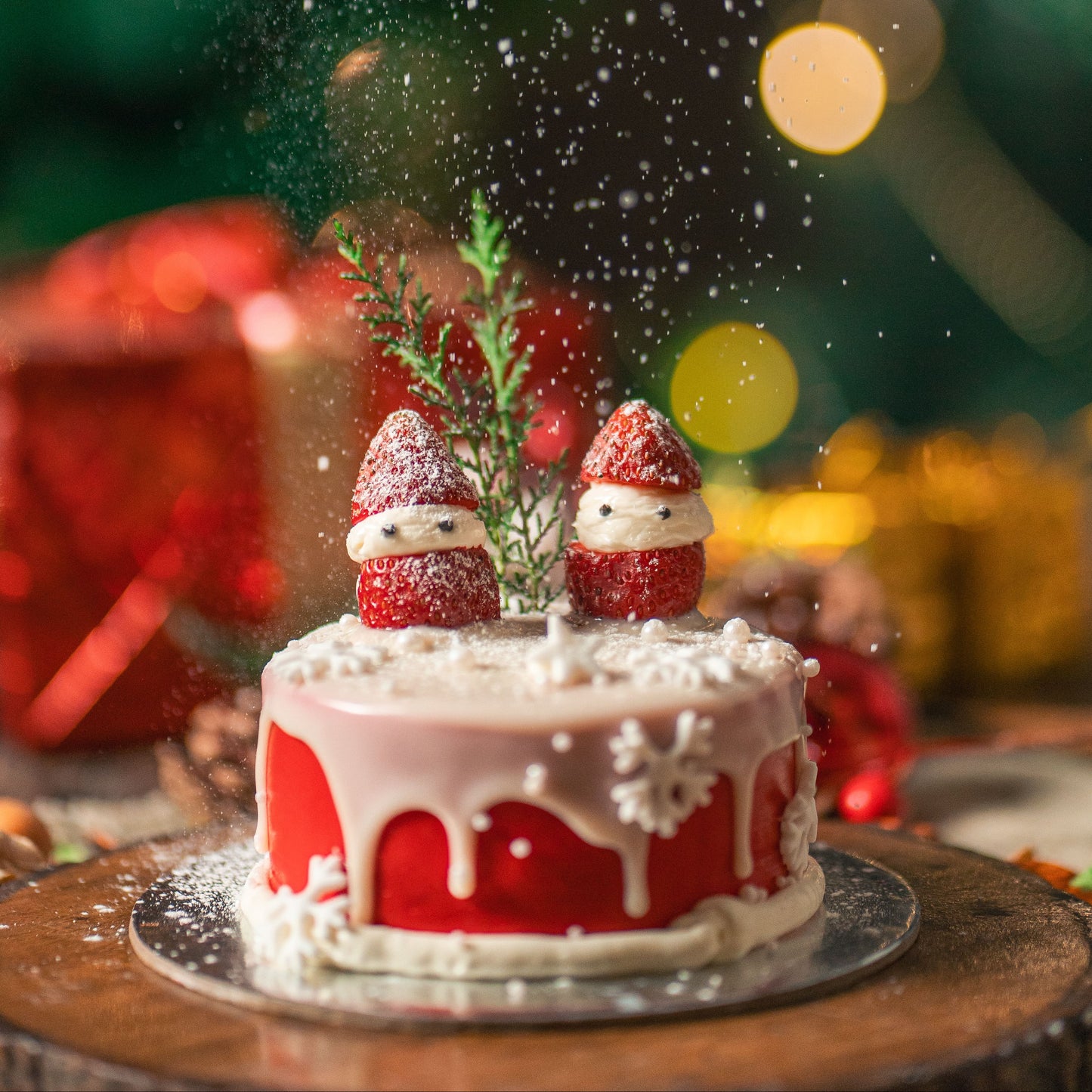 Red and white cake with Santa hats on a wooden table with festive lights in the background