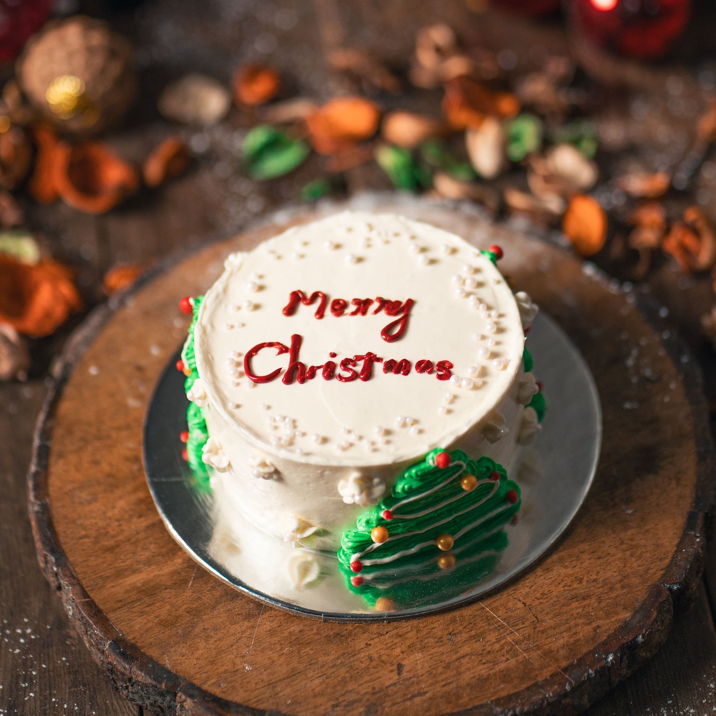 Small Christmas cake with 'Merry Christmas' on a rustic wooden surface.