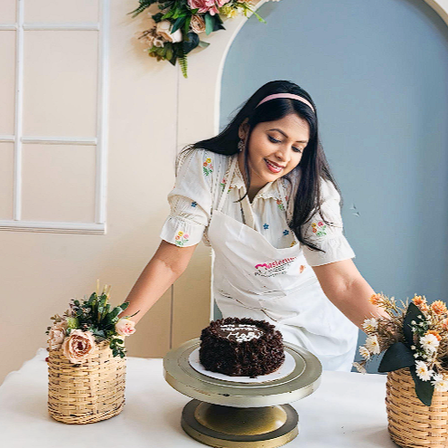 Woman in a kitchen setting with a cake and floral decorations for cake baking date where one can feel self love, Healing and self reward. 